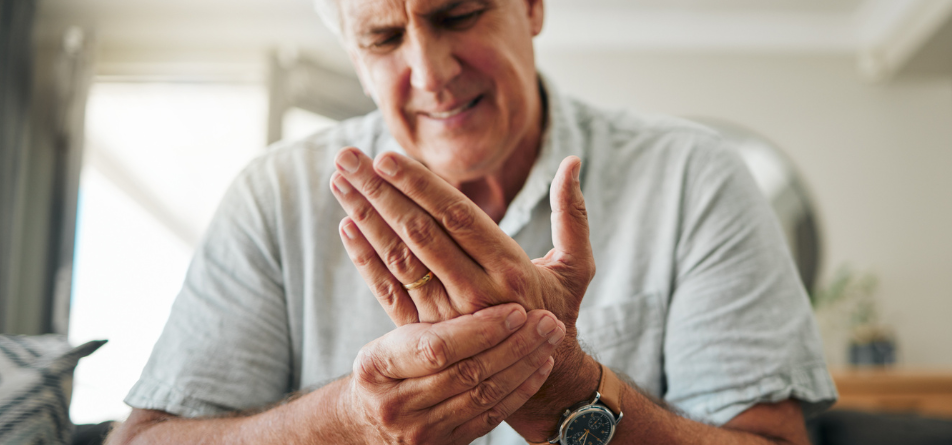 Mann mit Arthritis in den Fingern hält schmerzhaft ihr Handgelenk