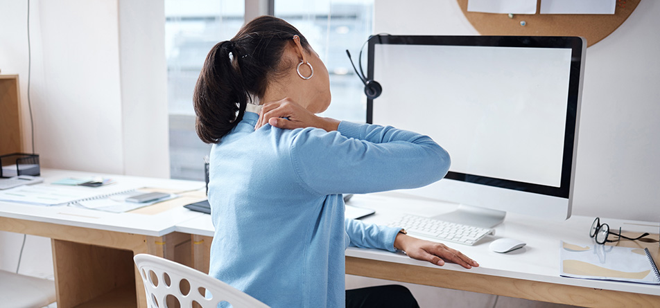Frau mit Nackenschmerzen am Schreibtisch